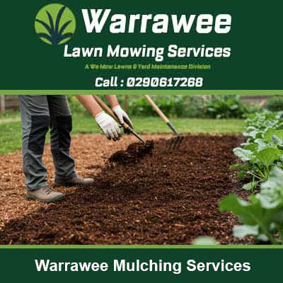 Worker spreading dark mulch with garden bed in Warrawee